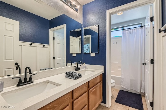 full bathroom featuring toilet, shower / bath combination with curtain, a sink, and a textured wall