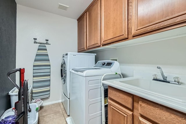 washroom featuring cabinets, sink, washing machine and dryer, and light tile patterned floors