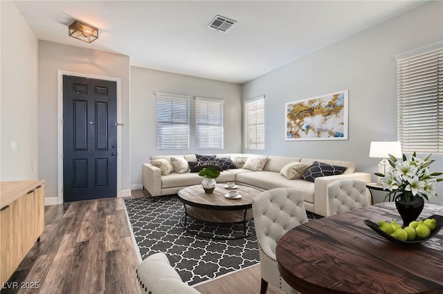 living area with dark wood-style floors, baseboards, and visible vents