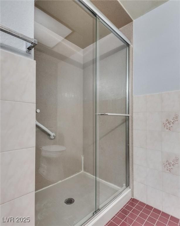 bathroom with walk in shower, toilet, tile patterned flooring, and tile walls