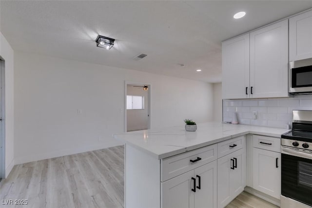 kitchen featuring stainless steel appliances, kitchen peninsula, and white cabinets