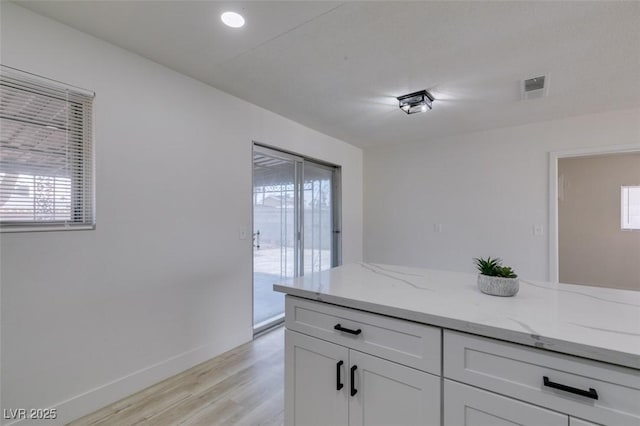 kitchen with white cabinetry, light stone countertops, and light hardwood / wood-style floors