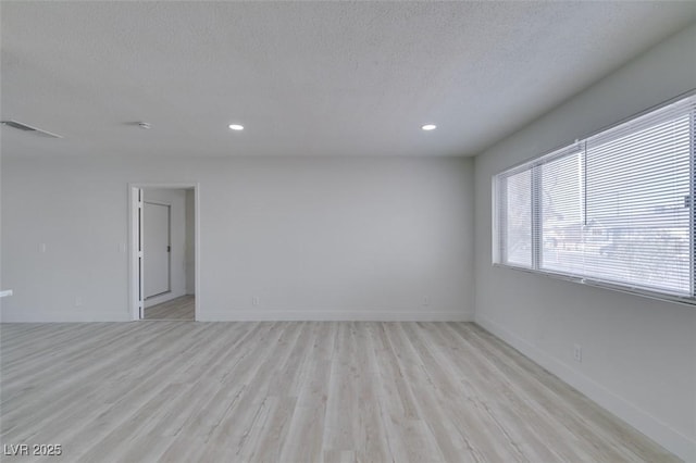 empty room featuring a textured ceiling and light hardwood / wood-style flooring