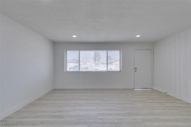 unfurnished room with a textured ceiling and light wood-type flooring