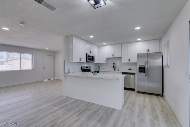 kitchen featuring stainless steel appliances, white cabinetry, sink, and light wood-type flooring