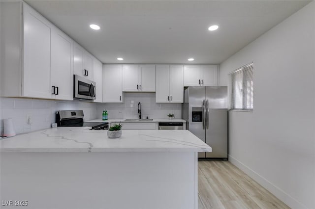 kitchen featuring white cabinetry, appliances with stainless steel finishes, sink, and kitchen peninsula