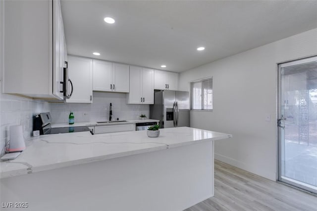 kitchen with sink, white cabinetry, kitchen peninsula, stainless steel appliances, and light stone countertops