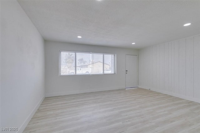 unfurnished room with light hardwood / wood-style flooring and a textured ceiling