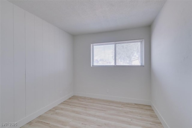 unfurnished room featuring a textured ceiling and light wood-type flooring