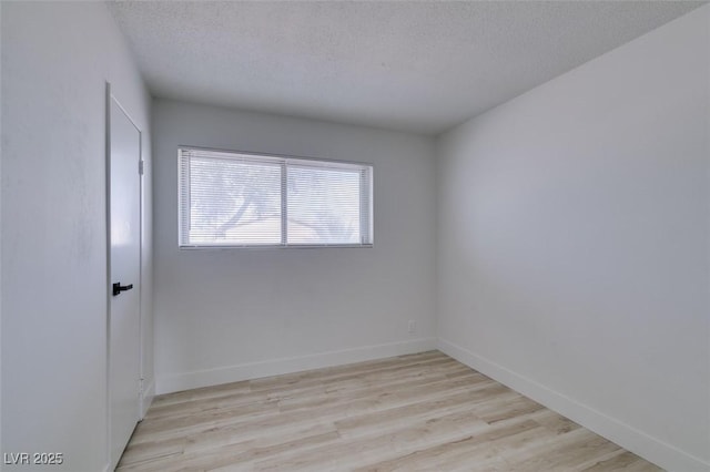 spare room with light hardwood / wood-style floors and a textured ceiling