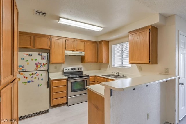 kitchen with sink, stainless steel range with electric stovetop, white refrigerator, a textured ceiling, and kitchen peninsula