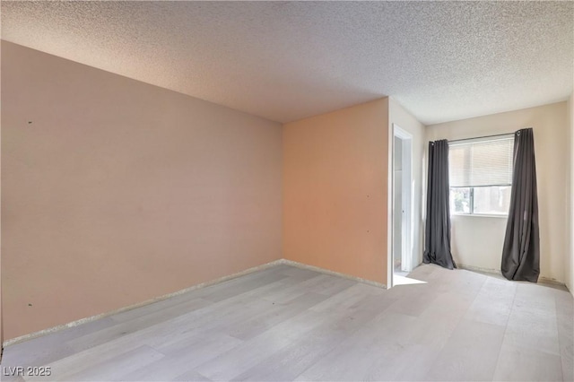 empty room featuring a textured ceiling and light hardwood / wood-style floors