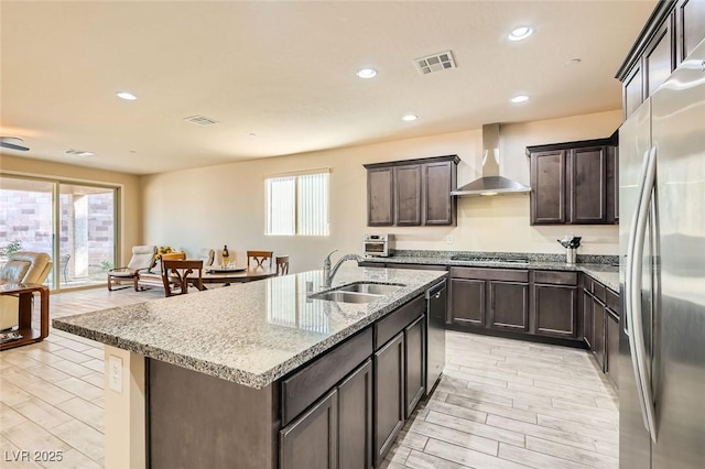 kitchen featuring sink, plenty of natural light, stainless steel appliances, an island with sink, and wall chimney exhaust hood