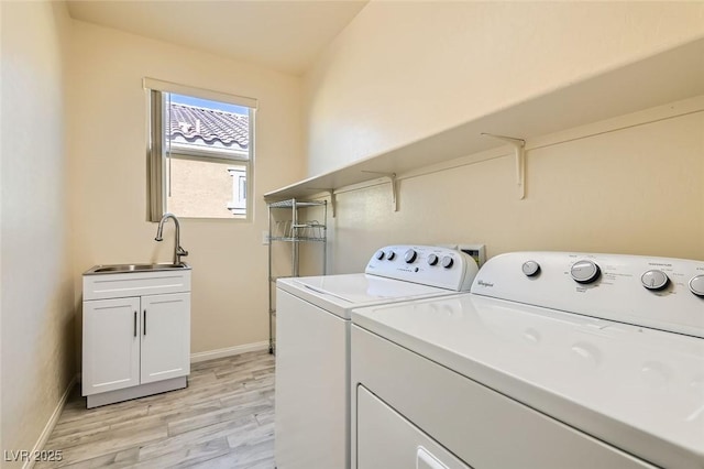 washroom with separate washer and dryer, sink, light hardwood / wood-style flooring, and cabinets