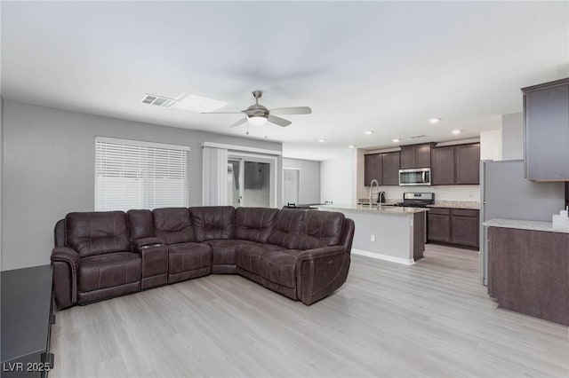 living room with ceiling fan, light hardwood / wood-style floors, and sink