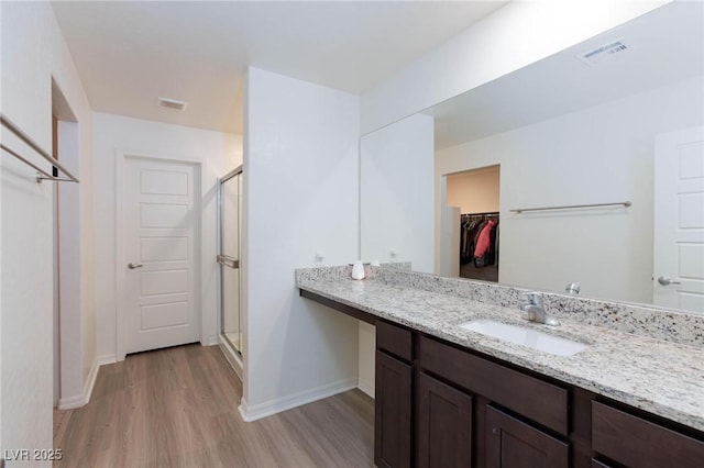 bathroom featuring walk in shower, wood-type flooring, and vanity