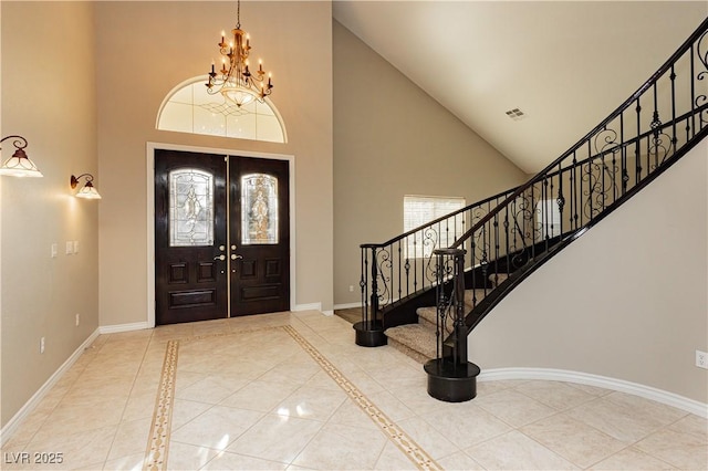 foyer with french doors, a towering ceiling, a chandelier, and light tile patterned flooring