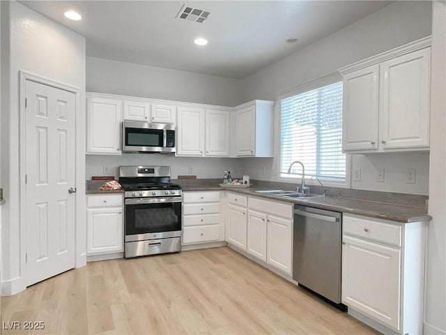 kitchen featuring sink, light hardwood / wood-style floors, white cabinets, and appliances with stainless steel finishes