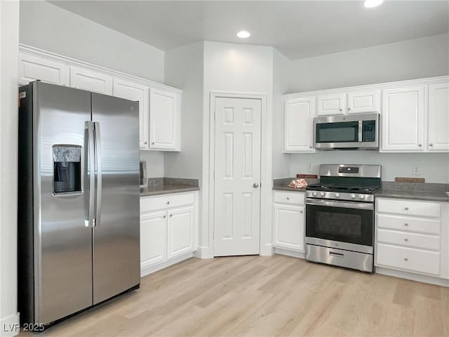 kitchen with light hardwood / wood-style flooring, stainless steel appliances, and white cabinets