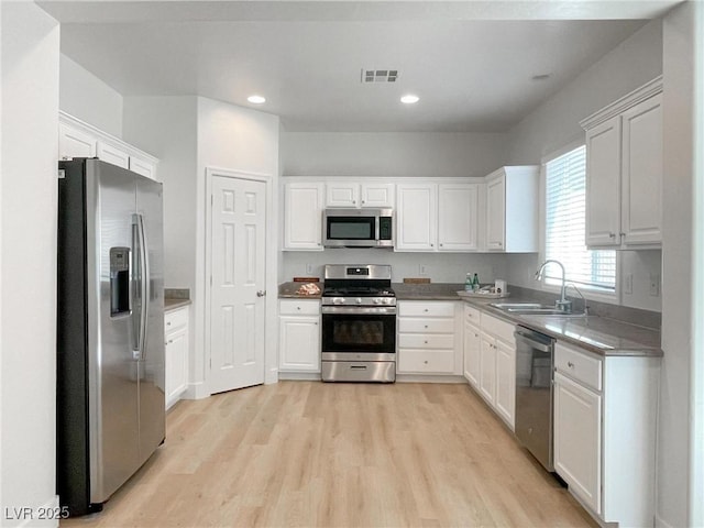 kitchen featuring sink, light hardwood / wood-style flooring, white cabinets, and appliances with stainless steel finishes