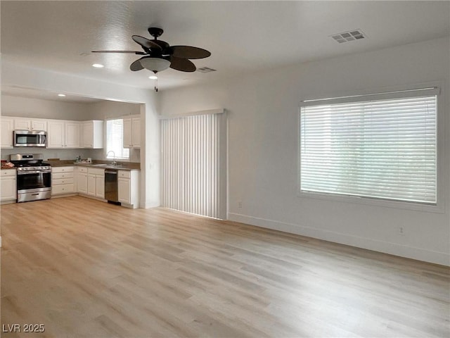 kitchen featuring sink, white cabinetry, light wood-type flooring, ceiling fan, and stainless steel appliances