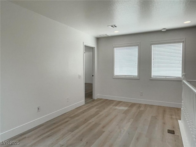 spare room featuring plenty of natural light, a textured ceiling, and light hardwood / wood-style flooring