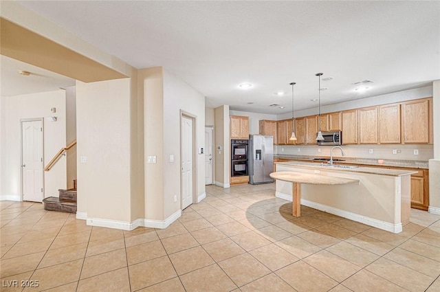 kitchen with light tile patterned floors, a breakfast bar, appliances with stainless steel finishes, hanging light fixtures, and an island with sink