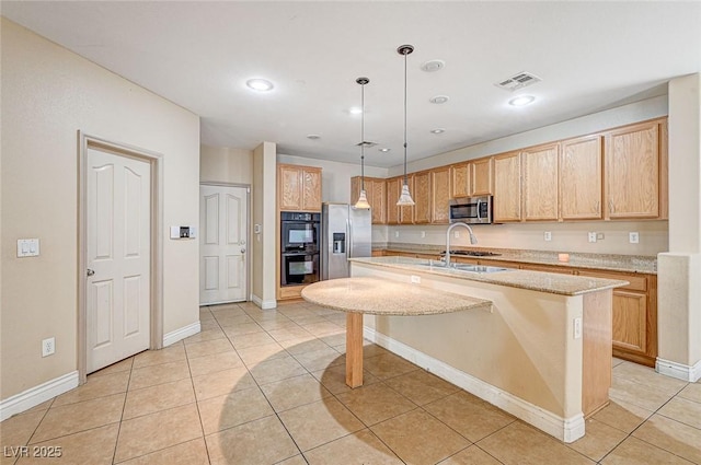 kitchen featuring light tile patterned flooring, hanging light fixtures, a kitchen breakfast bar, stainless steel appliances, and a kitchen island with sink