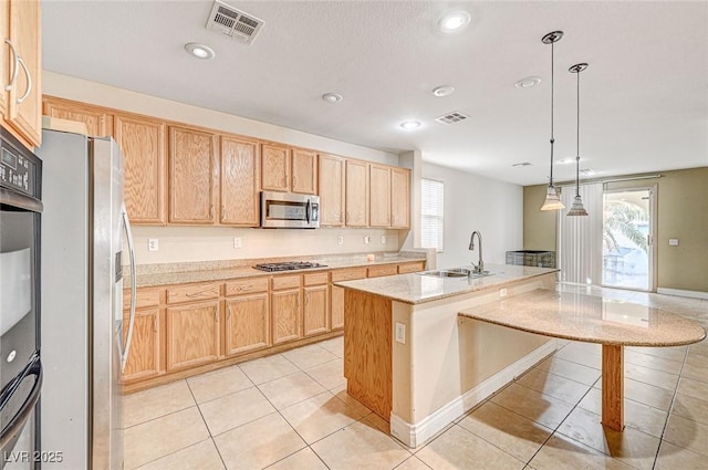 kitchen featuring sink, appliances with stainless steel finishes, hanging light fixtures, a center island with sink, and light tile patterned flooring