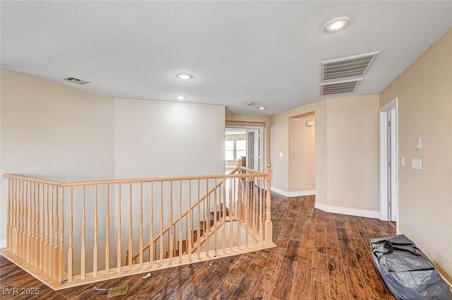 corridor with hardwood / wood-style floors and a textured ceiling