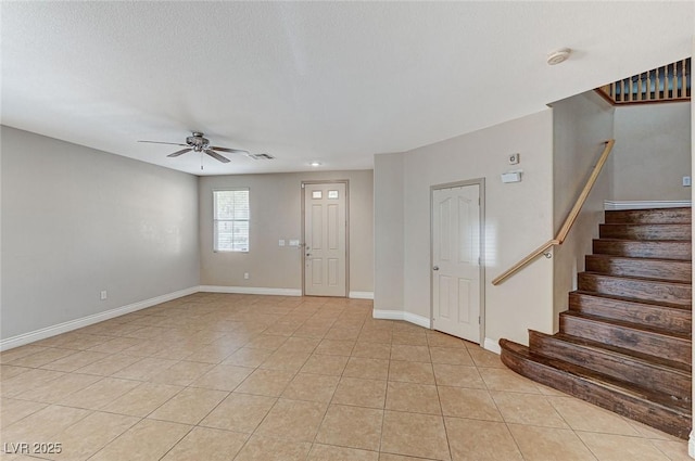 foyer with ceiling fan, a textured ceiling, and light tile patterned floors