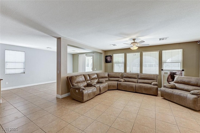 tiled living room featuring ceiling fan, a healthy amount of sunlight, and a textured ceiling