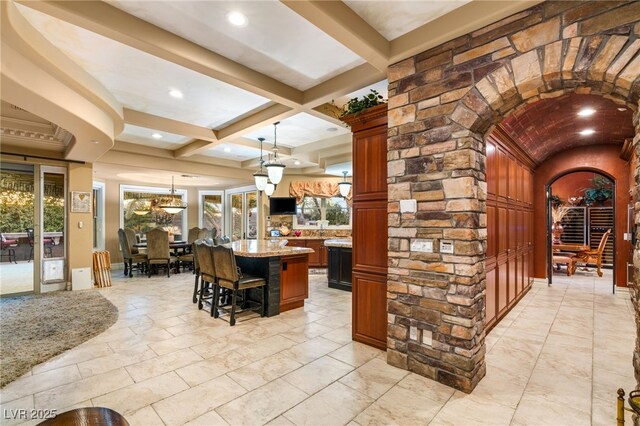 609 China Doll Pl, Henderson, NV 89012 - interior space featuring pendant lighting, a breakfast bar, beam ceiling, light stone counters, and a kitchen island