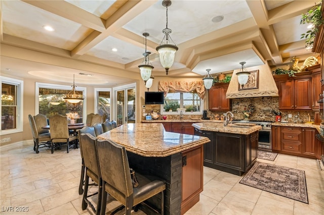 609 China Doll Pl, Henderson, NV 89012 - kitchen with a breakfast bar area, a kitchen island with sink, hanging light fixtures, tasteful backsplash, and light stone countertops
