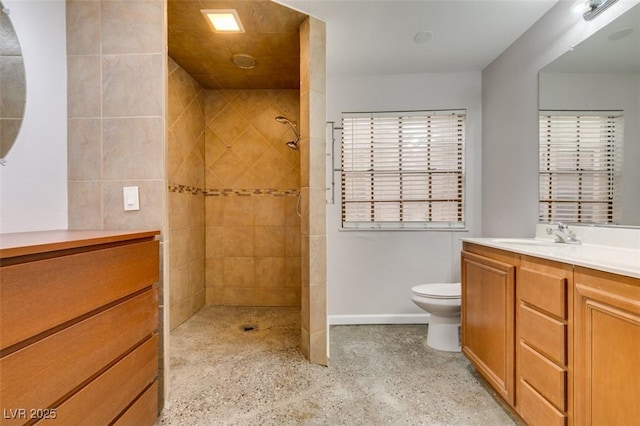 bathroom featuring a tile shower, vanity, a wealth of natural light, and toilet