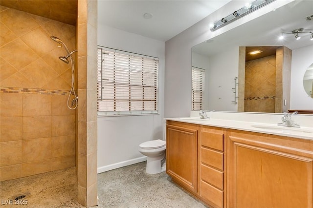 bathroom with vanity, a tile shower, and toilet