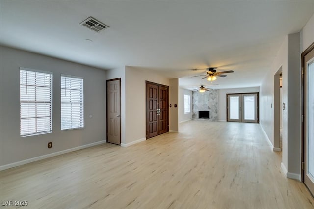 unfurnished living room featuring light hardwood / wood-style flooring, a premium fireplace, and ceiling fan