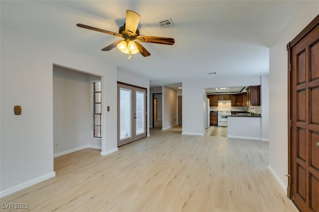 unfurnished living room featuring french doors, sink, ceiling fan, and light hardwood / wood-style flooring