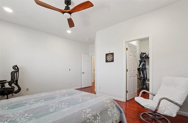 bedroom with a walk in closet, dark hardwood / wood-style floors, and ceiling fan