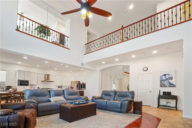 living room featuring light tile patterned flooring, ceiling fan, and a high ceiling