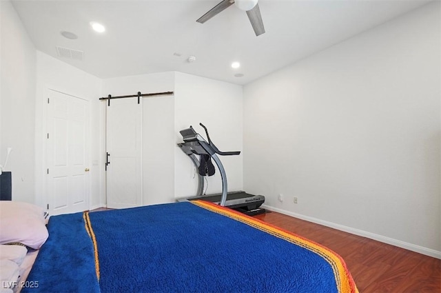 exercise area with hardwood / wood-style floors, a barn door, and ceiling fan