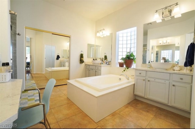 bathroom featuring tile patterned flooring, vanity, and a bath