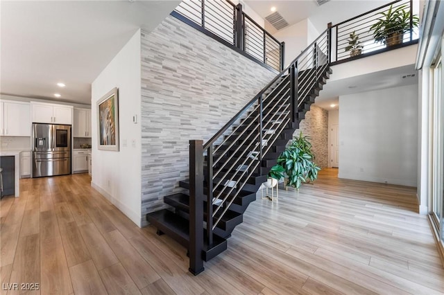 staircase with a towering ceiling and hardwood / wood-style floors