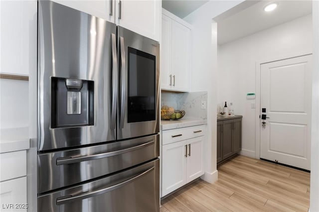 kitchen with white cabinetry, stainless steel refrigerator with ice dispenser, backsplash, and light hardwood / wood-style flooring