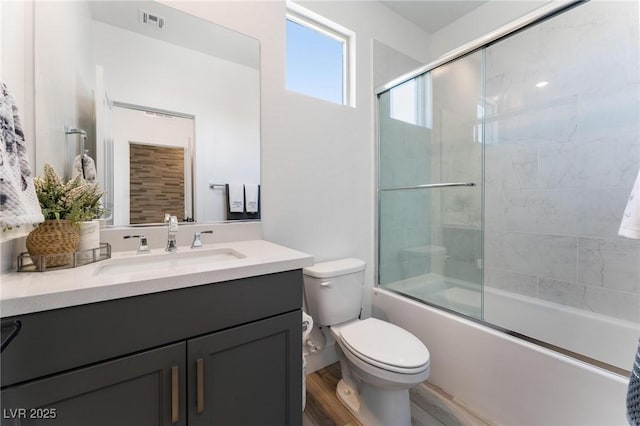 full bathroom with vanity, toilet, hardwood / wood-style floors, and combined bath / shower with glass door