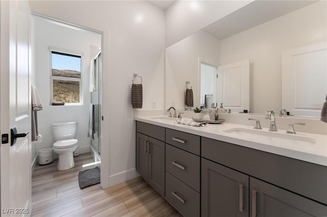 bathroom featuring a shower with door, vanity, and toilet