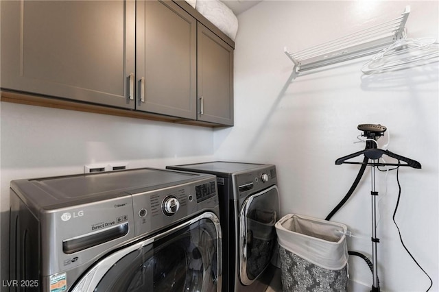 clothes washing area with cabinets and washer and clothes dryer