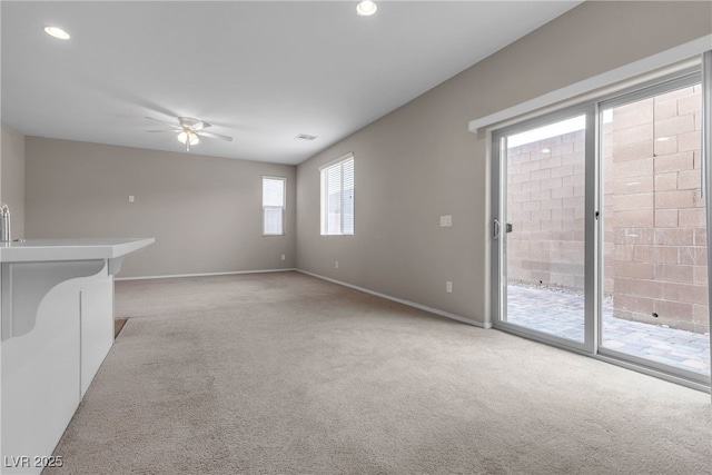 unfurnished living room with ceiling fan, visible vents, baseboards, and light colored carpet