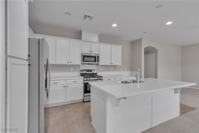 kitchen with arched walkways, a breakfast bar, a sink, white cabinetry, and appliances with stainless steel finishes