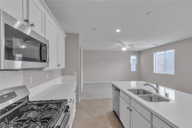 kitchen featuring white cabinets, ceiling fan, appliances with stainless steel finishes, light countertops, and a sink